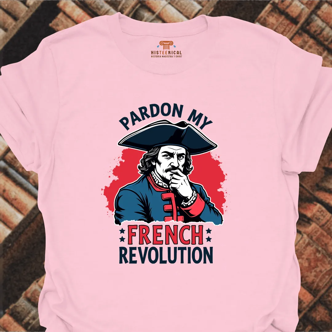 Pink t-shirt with a graphic of a historical figure and text 'Pardon My French Revolution' on a brick background.
