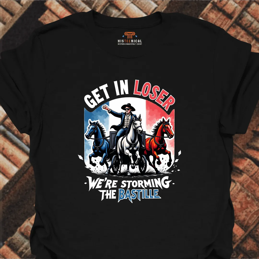 Black t-shirt with graphic design of a man on horseback and text 'Get in Loser, We're Storming the Bastille' on a brick background.