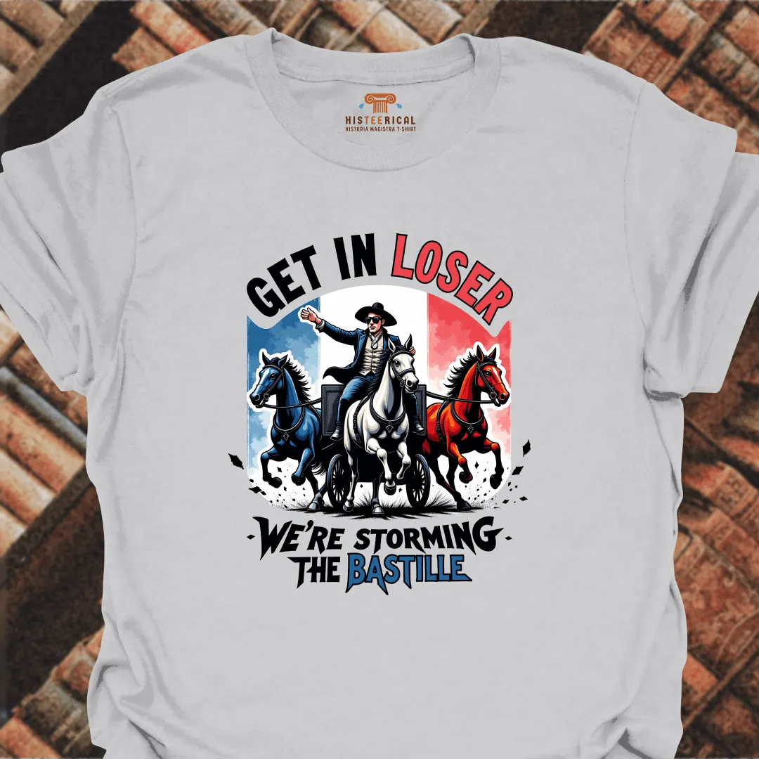 Gray t-shirt with graphic design of a man on horseback and text 'Get in Loser, We're Storming the Bastille' on a brick background.
