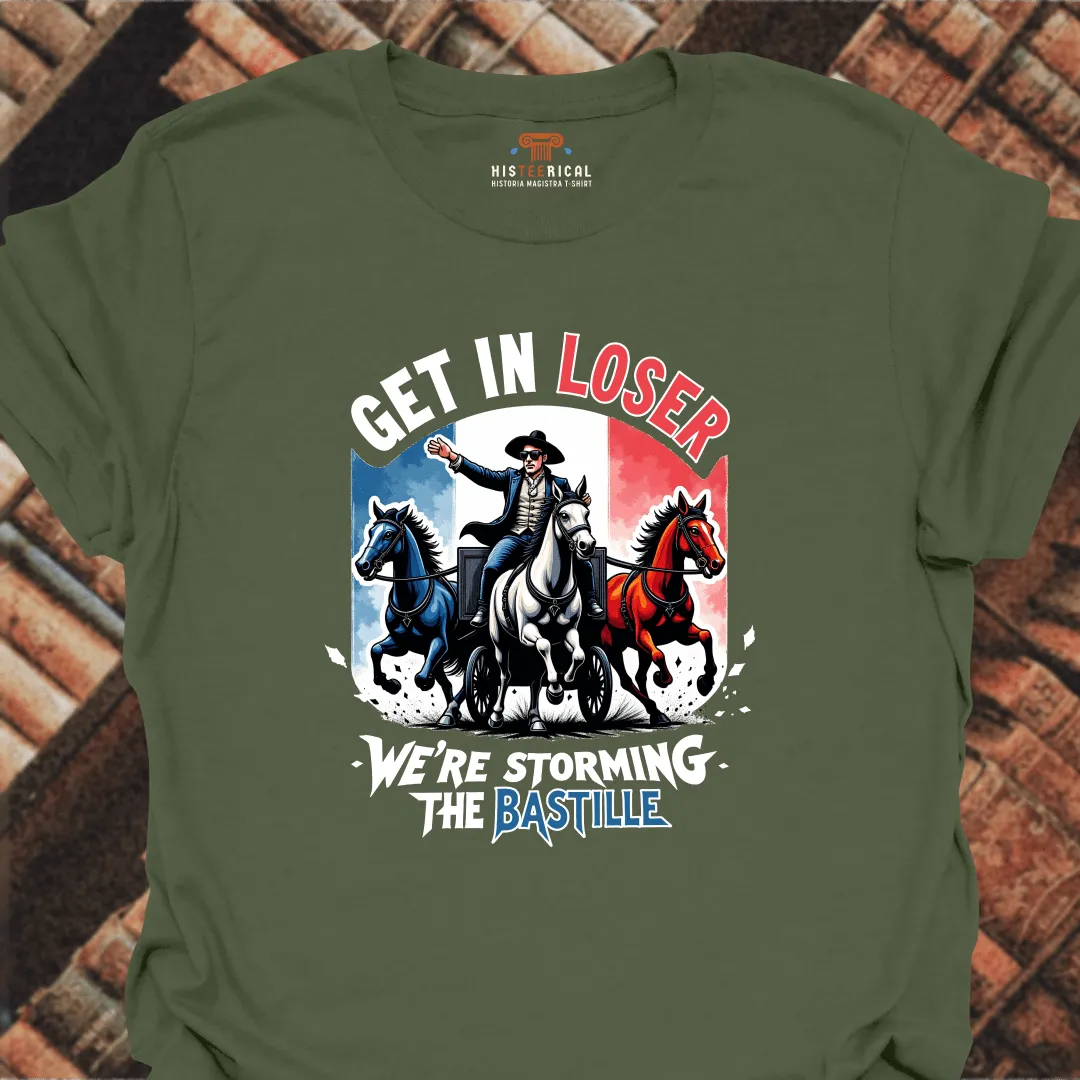 Green t-shirt with graphic design of a man on horseback and text 'Get in Loser, We're Storming the Bastille' on a brick background.