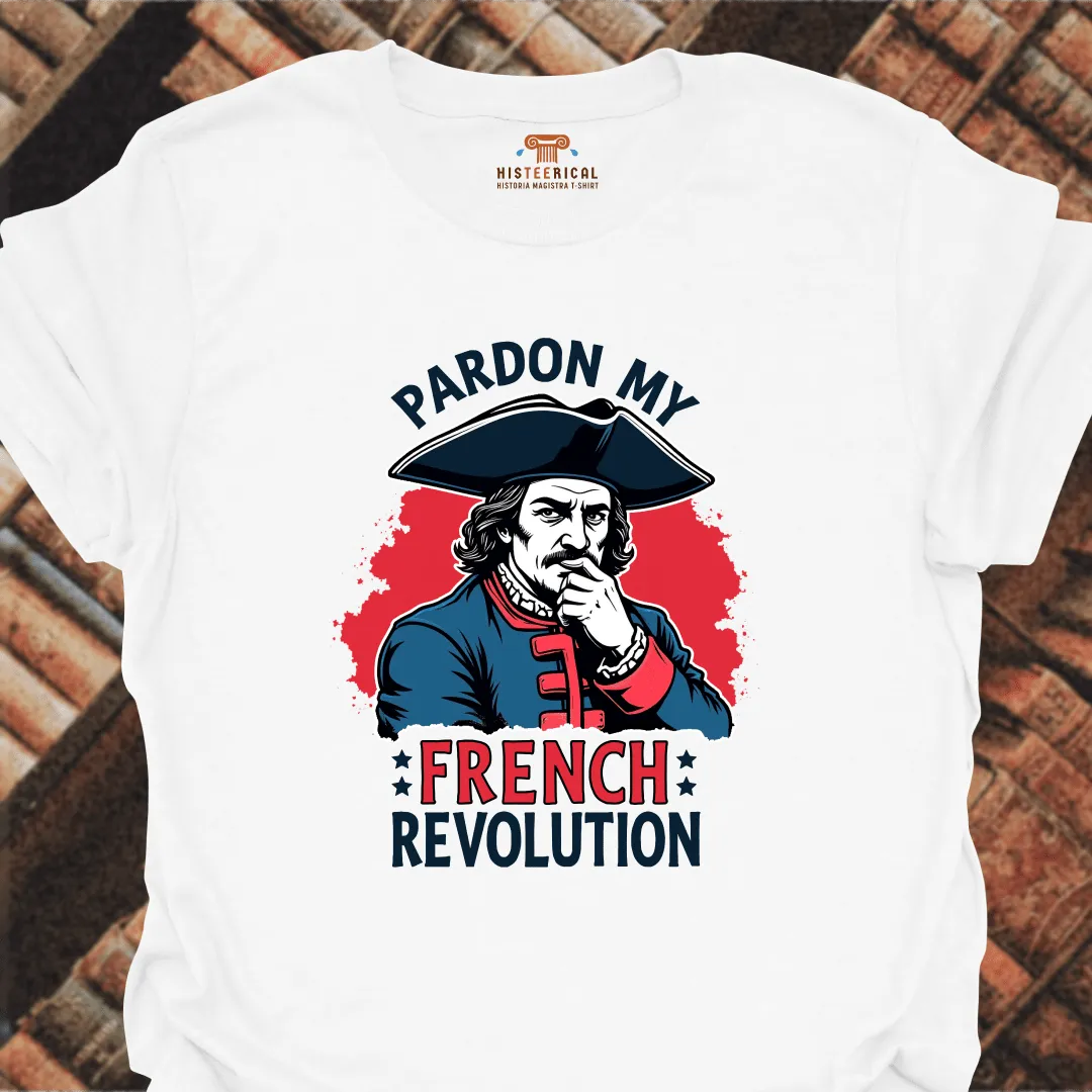 White t-shirt with a graphic of a historical figure and text 'Pardon My French Revolution' on a brick background.